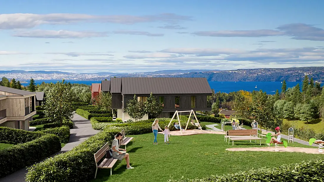 Lekeplass foran mørk trehusfasade med Oslofjorden i bakgrunnen